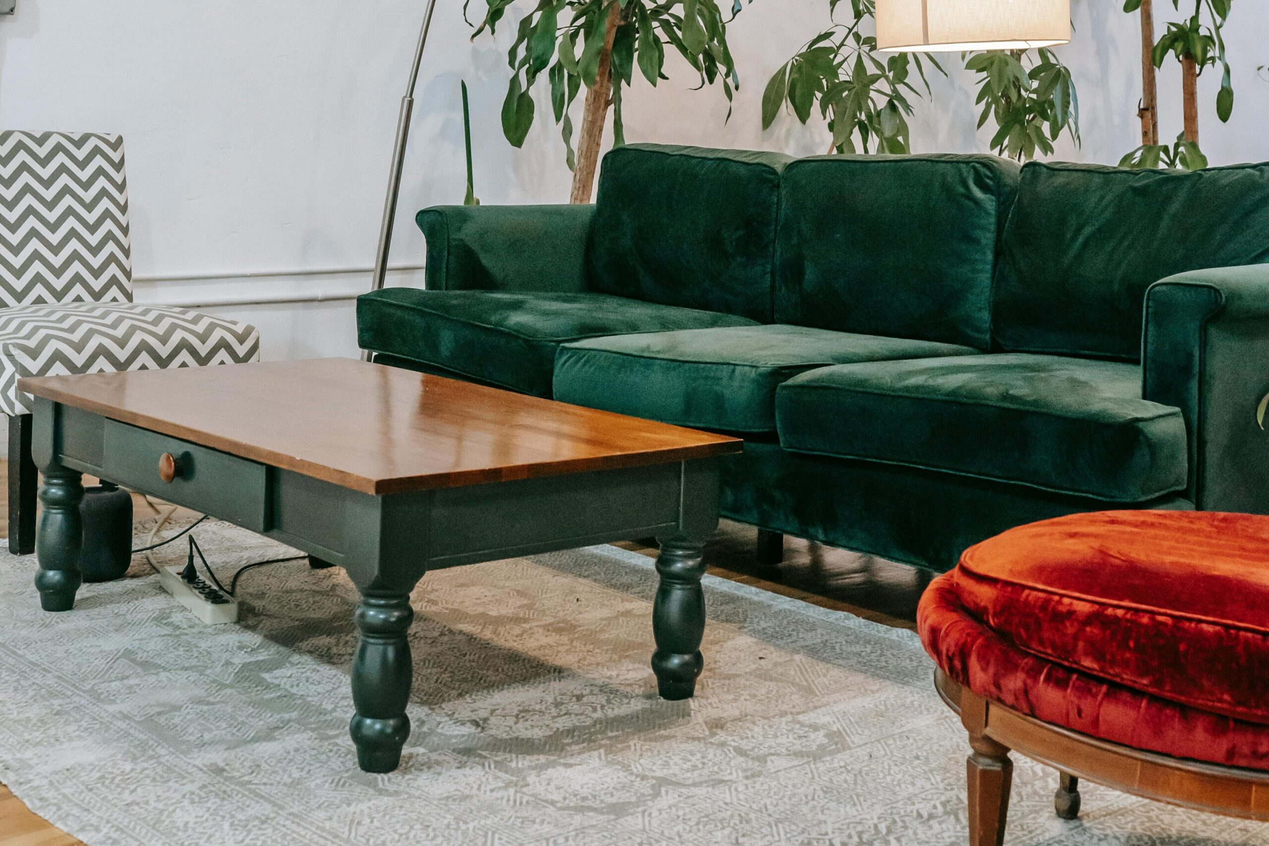 Inviting living room featuring a green velvet sofa, lush indoor plants, and a modern aesthetic.
