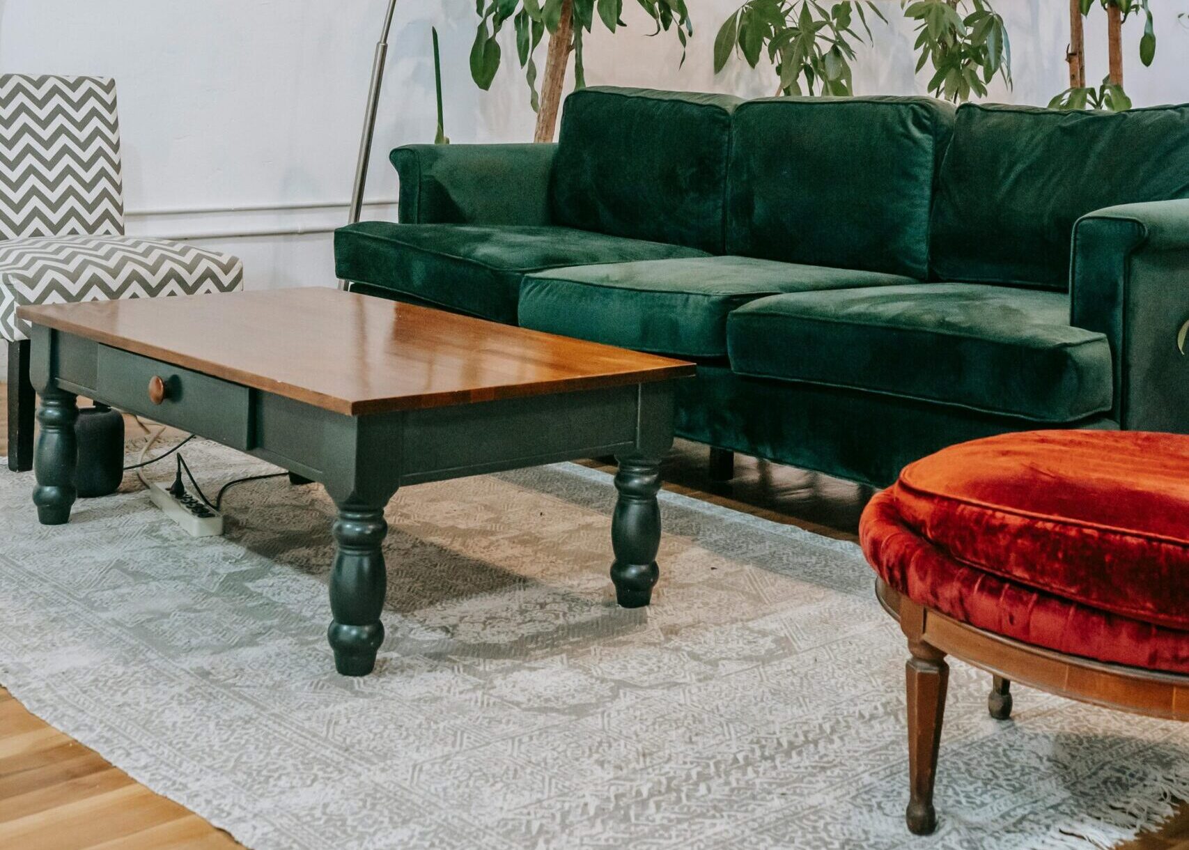 Inviting living room featuring a green velvet sofa, lush indoor plants, and a modern aesthetic.