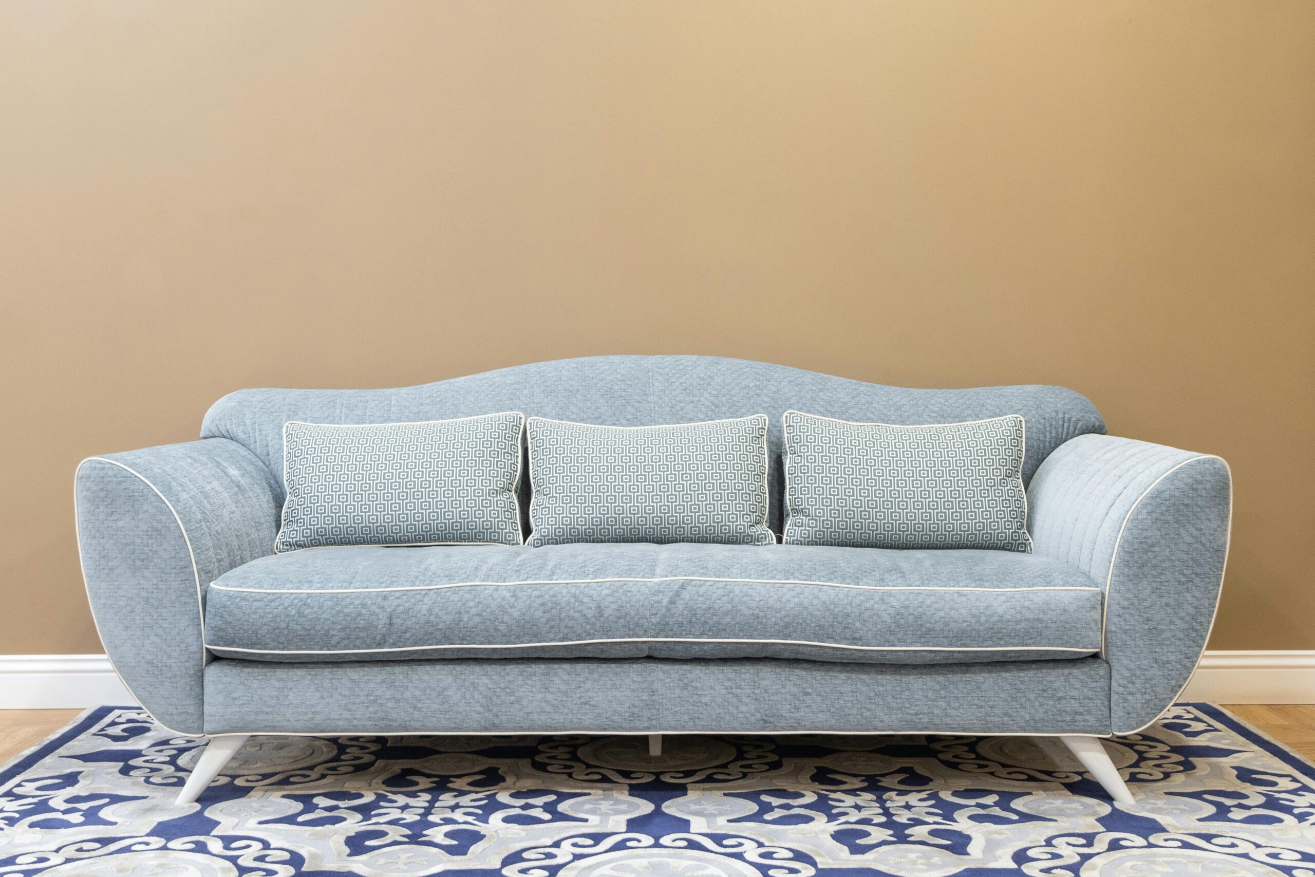 Stylish blue sofa with cushions on patterned carpet, perfect for a modern, cozy living space.